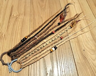 May include: A set of brown, blonde, and black synthetic dreadlocks with beads and feathers. The dreadlocks are tied together with a blue elastic band.