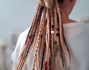 May include: A person with blonde hair wearing brown, blonde, and black dreadlocks with beads and feathers.
