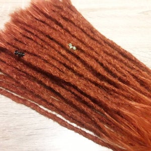 May include: A set of long, auburn-colored synthetic dreadlocks. The dreadlocks are made of kanekalon hair and are ready to be installed.