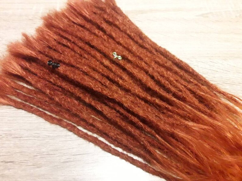 May include: A set of long, auburn-colored synthetic dreadlocks. The dreadlocks are made of kanekalon hair and are ready to be installed.