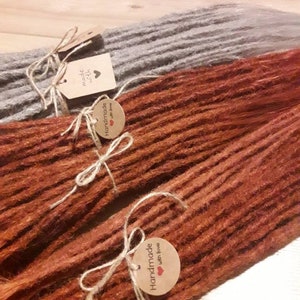 May include: Two sets of handmade dreadlocks, one set is a light brown color and the other is a dark brown color. Both sets have a tag that says "Handmade with love".