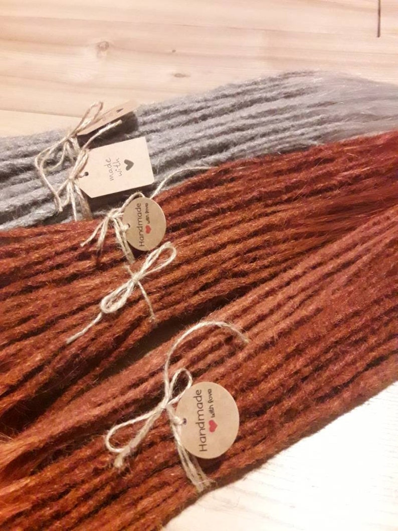 May include: Two sets of handmade dreadlocks, one set is a light brown color and the other is a dark brown color. Both sets have a tag that says "Handmade with love".