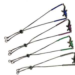 May include: Four adjustable bracelets with black chains and crystal accents. Each bracelet features a different colored lizard charm with crystal embellishments. The colors are blue, pink, green, and black.
