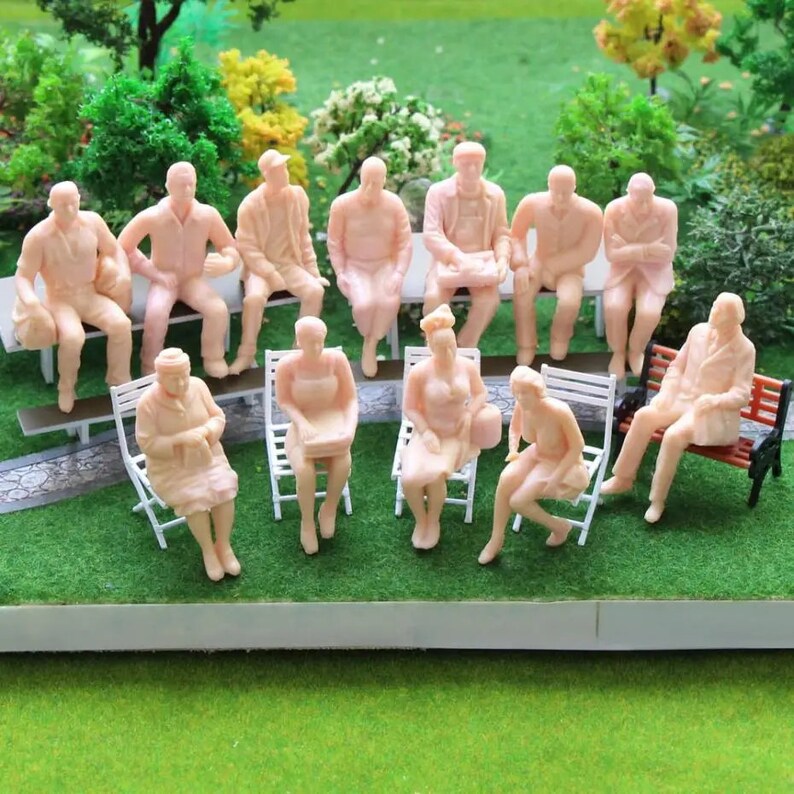 May include: A set of 13 miniature plastic figures of people sitting on benches and chairs. The figures are all in a light pink color and are about 1 inch tall.