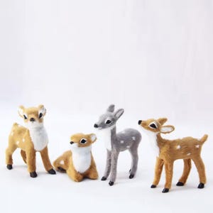 May include: Four decorative deer figurines in various poses. Two are standing, one is lying down, and one is looking up. The deer are tan, gray, and white with black hooves. The figurines have white spots.