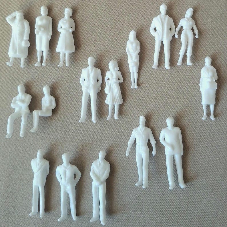 May include: A collection of small, white plastic figurines depicting various human figures in different poses. The figurines include standing, sitting, and walking figures, suitable for architectural models or miniature scenes.