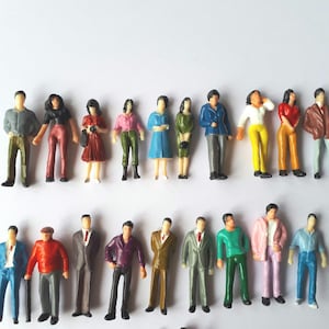 Può includere: Figurine in miniatura di persone in vari abiti, tra cui abiti e completi. Le figure sono dipinte in vari colori e disposte su due file. Queste piccole figure sono adatte per modelli architettonici o diorami.