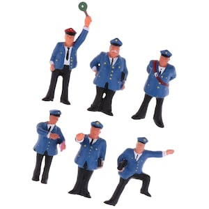 以下が含まれることがあります： 青い制服と帽子を着用した列車の車掌のミニチュアフィギュア6体セット。フィギュアは、旗を持っている、本を持っている、腰に手を当てて立っているなど、さまざまなポーズをとっています。