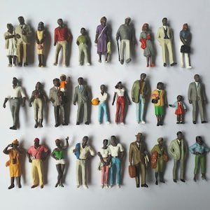 May include: A collection of 30 miniature plastic figures of people in various poses and clothing. The figures are all black and are wearing a variety of clothing, including dresses, pants, shirts, and hats. The figures are all standing on a white surface.