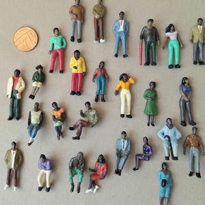 Puede incluir: Una colecci&oacute;n de figuras en miniatura que representan a personas en varias poses y atuendos. Las figuras est&aacute;n pintadas en una variedad de colores, incluyendo verde, amarillo, rojo y azul. Se incluye una moneda para la escala.