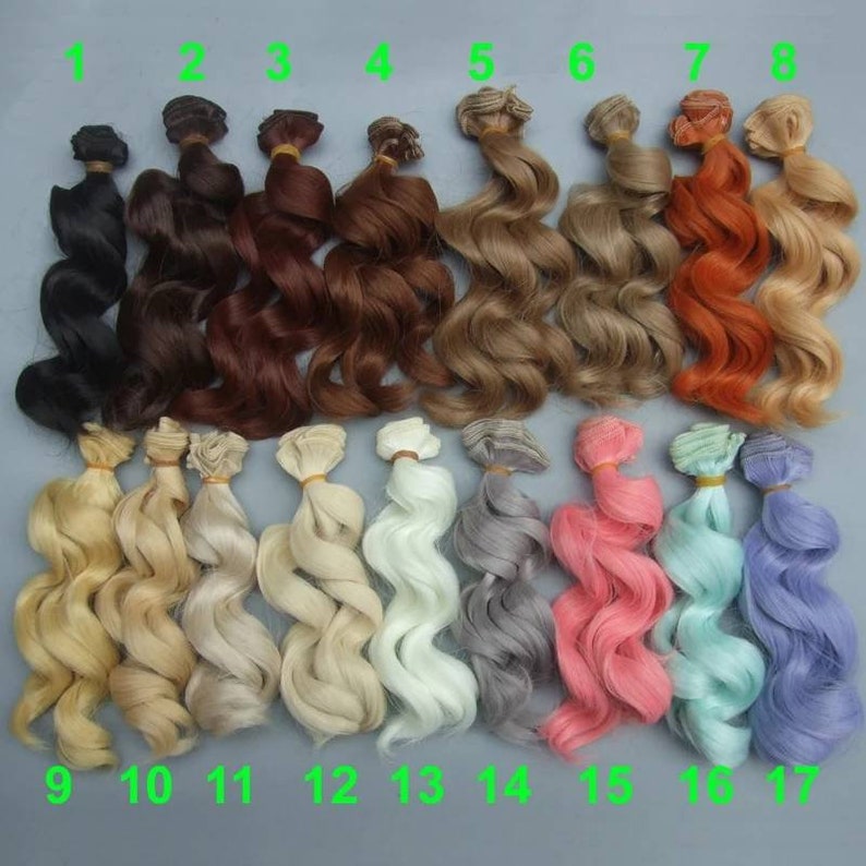 May include: A set of 17 doll hair wefts in various colors, including black, brown, blonde, white, gray, pink, and blue. The wefts are wavy and have a clip at the top for easy attachment.