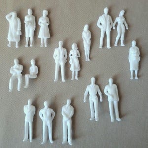 May include: A collection of small, white architectural figures in various poses. The figures include standing, sitting, and walking people, and are likely used for model building or architectural design projects. The figures are all white and appear to be made of plastic.