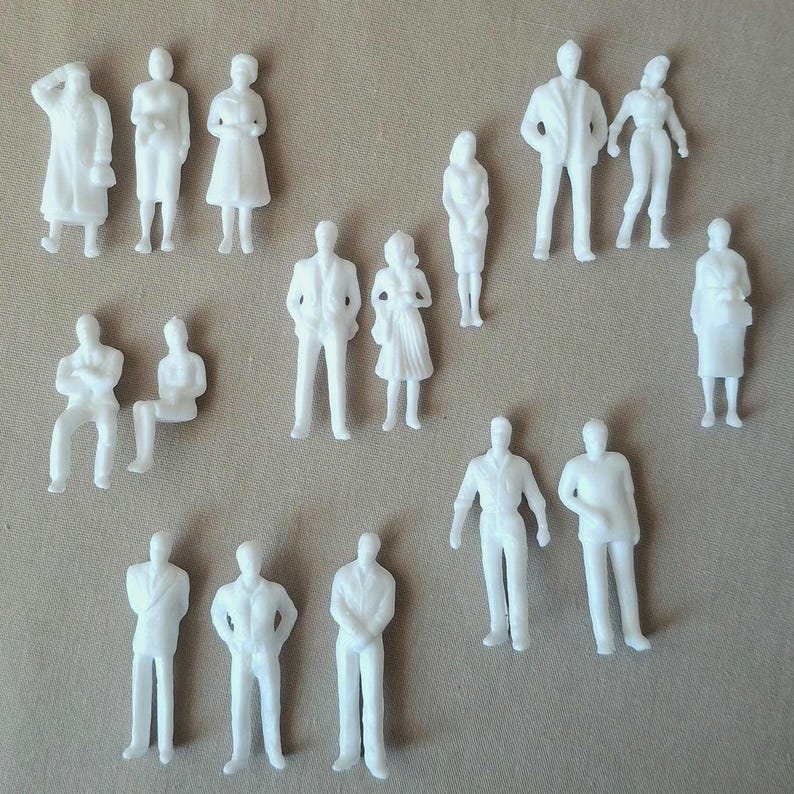May include: A collection of small, white architectural figures in various poses. The figures include standing, sitting, and walking people, and are likely used for model building or architectural design projects. The figures are all white and appear to be made of plastic.