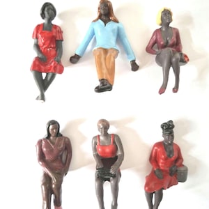 Peut inclure: Six figurines miniatures de personnes assises. Les figurines sont toutes vêtues de vêtements différents, notamment du rouge, du bleu et du marron. Les figurines sont en plastique et mesurent environ 5 cm de haut.