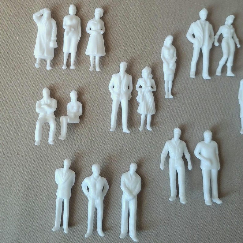 May include: A collection of small, white plastic figurines depicting people in various poses. The figures include standing, sitting, and walking individuals, suitable for architectural models or miniature scenes.