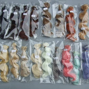 May include: Assortment of 14 different colored doll hair pieces in individual plastic bags. The hair is in various lengths and textures, including straight, wavy, and curly.