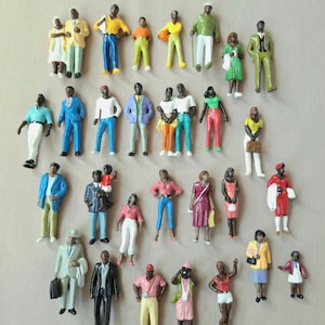May include: A collection of miniature figurines depicting people in various outfits. The figurines are painted in a variety of colors, including blue, green, yellow, and red. Some figurines are holding accessories like briefcases and purses. The figurines are standing.