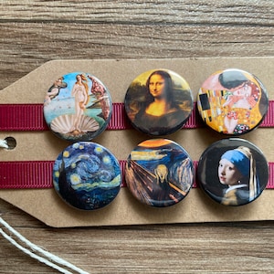 Könnte beinhalten: Sechs runde Knöpfe mit Bildern berühmter Gemälde. Die Knöpfe sind in zwei Reihen zu je drei angeordnet. Die obere Reihe zeigt Die Geburt der Venus, Mona Lisa und Der Kuss. Die untere Reihe zeigt Die Sternennacht, Der Schrei und Mädchen mit dem Perlenohrring.