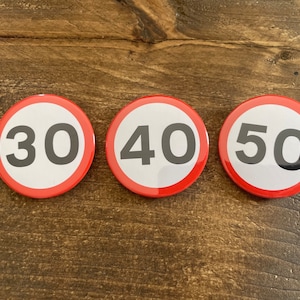Op de afbeelding: Drie ronde rode en witte verkeersborden met zwarte cijfers. De borden geven 30, 40 en 50 aan.