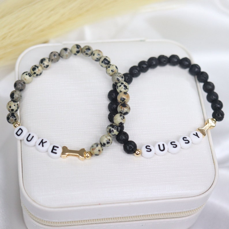 Puede incluir: Dos pulseras de cuentas con nombres personalizados, "DUKE" y "SUSSY", deletreados con cuentas de letras blancas. Las pulseras est&aacute;n hechas con cuentas de lava negra y cuentas de jaspe dalmata blanco y negro.