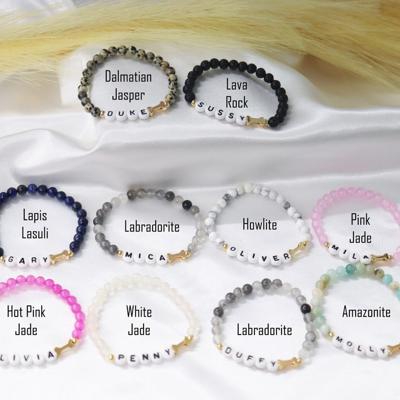 Peut inclure: Plusieurs bracelets de perles de pierres pr&eacute;cieuses, dont le jaspe dalmatien, la roche de lave, le lapis-lazuli, la labradorite, l'howlite, le jade rose, le jade rose vif, le jade blanc et l'amazonite. Chaque bracelet a un charme d'os dor&eacute; et un nom.