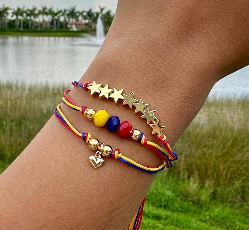 May include: Three layered bracelets with red, yellow, and blue string, gold star charms, and small gold heart charm.