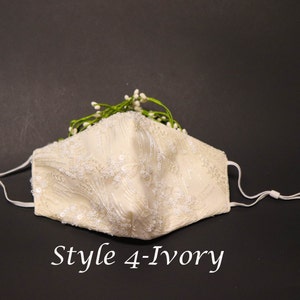 May include: Ivory white face mask with delicate lace and bead embellishments. The mask has adjustable elastic ear loops and is decorated with a sprig of white flowers.