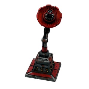 Peut inclure: Une miniature de tour de surveillance rouge et grise avec une antenne rotative. La tour a une base carrée avec un motif rouge et gris et une série de petits détails dorés.