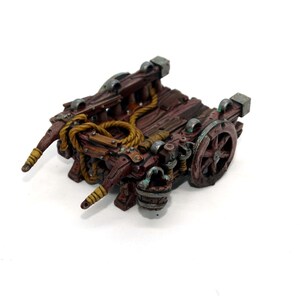 May include: A wooden miniature cart with a rope, a bucket, and a wheel. The cart is painted brown with green and silver accents.