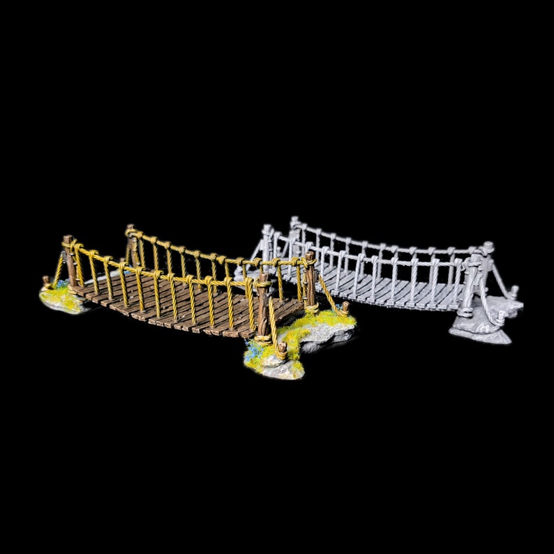 May include: Two miniature rope bridges, one painted brown and yellow, the other painted grey. Both bridges are made of wood and rope and have a stone base.