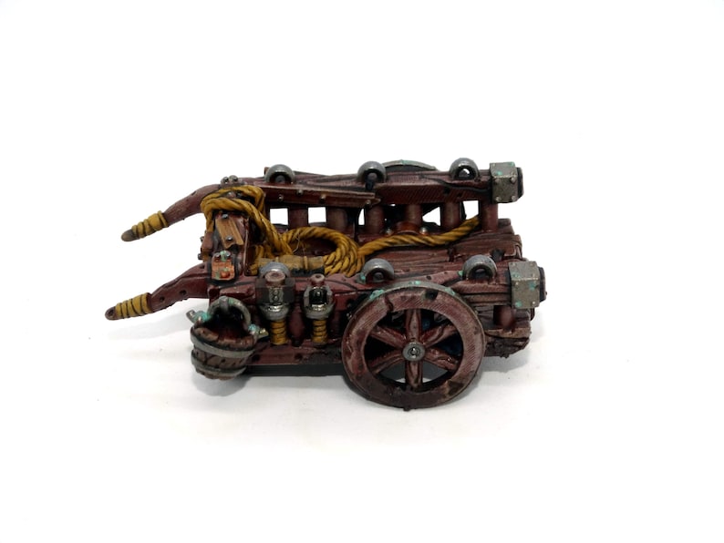 May include: A wooden siege weapon with a rope and a large wheel. The weapon is painted brown and has metal accents.