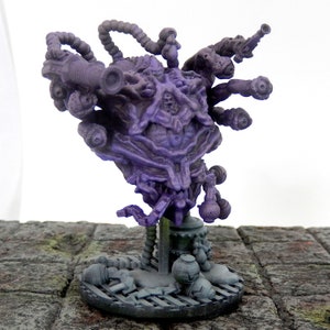 Puede incluir: Figura detallada de criatura de fantasía púrpura con múltiples apéndices y un diseño complejo y texturizado. La figura está montada sobre una base gris con elementos esculpidos adicionales, lo que sugiere un tema de ciencia ficción o fantasía.