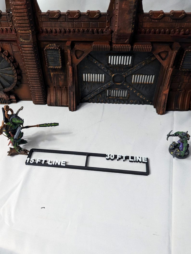 May include: Black plastic ruler with white text that reads "15 FT LINE" and "30 FT LINE". The ruler is on a white surface.