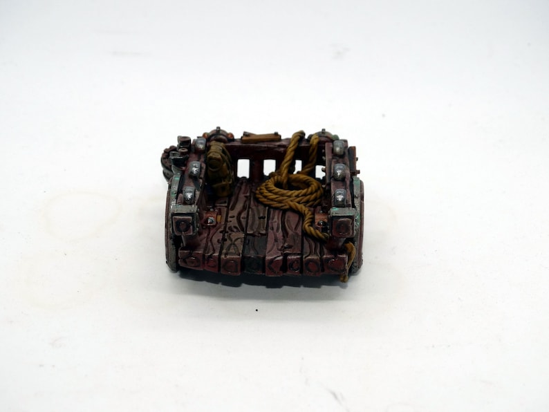 May include: A miniature wooden cart with metal accents and a rope tied to the back. The cart is painted brown with green and silver accents.