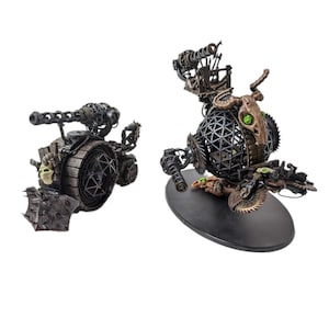 Könnte beinhalten: Zwei detaillierte, kunstvoll gefertigte, steampunk-artige Skulpturen aus Metall und Holz von mechanischen Kreaturen. Die Skulpturen sind in Braun-, Schwarz- und Grüntönen bemalt. Die Skulpturen stehen auf einem weißen Hintergrund.