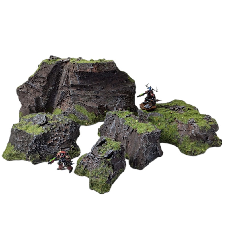 May include: A set of five rocky terrain pieces for tabletop gaming. The pieces are made of a dark gray material with green moss accents. The pieces are various sizes and shapes, and they are perfect for creating a realistic and detailed landscape for your games.