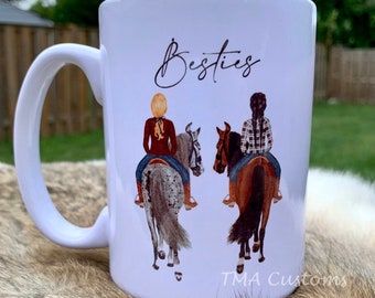 May include: White ceramic mug with a black and white illustration of two people riding horses. The mug has the word "Besties" written on it in black cursive.