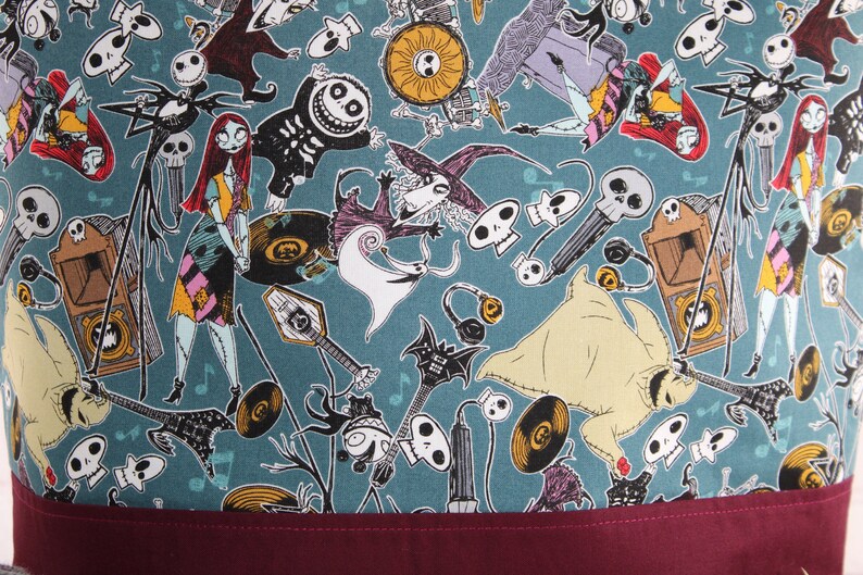 Może przedstawiać: Tkanina w kolorze turkusowym z powtarzającym się wzorem postaci z filmu Koszmar przed świętami. Postacie to Jack Skellington, Sally i Zero. Tkanina idealnie nadaje się do projekt&oacute;w rękodzielniczych, takich jak torby, poduszki i kołdry.