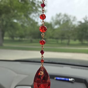May include: Red crystal car charm with a teardrop-shaped pendant and a chain of smaller red crystals.