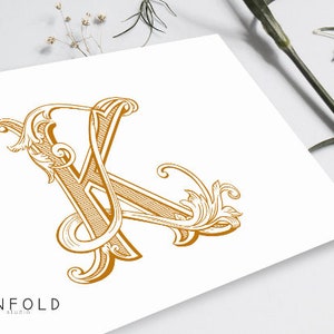 以下が含まれることがあります： 白い背景に、金色の装飾的な花柄の文字K。