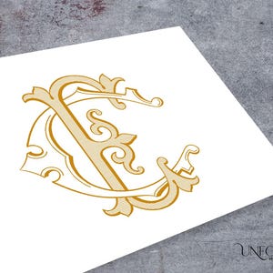 May include: Gold-colored monogram design featuring the letters "C" and "S" intertwined with ornate flourishes. The design is printed on a white surface, with the words "UNFOLD MONOGRAMS" in a script font at the bottom right.