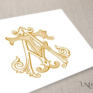 Puede incluir: Un diseño de monograma dorado con las letras entrelazadas "A" y "T" en un estilo vintage ornamentado. El diseño incluye adornos decorativos y está impreso sobre un fondo blanco. El logotipo de Unfold Studio es visible en la esquina inferior derecha.