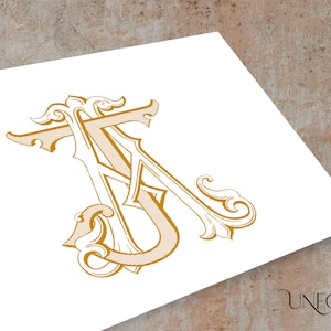 May include: A gold monogram with the letters "A" and "T" intertwined in a decorative, ornate font. The letters are surrounded by intricate flourishes and swirls.