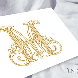 May include: Gold-colored monogram featuring the intertwined letters "M" and "A" in an ornate, vintage style. The design includes floral and scrollwork details, set against a white background. The word "UNFOLD STUDIO" is at the bottom.
