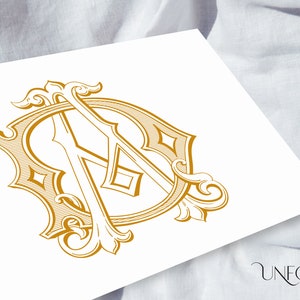 Puede incluir: Diseño de monograma dorado con las letras "A" y "D" entrelazadas dentro de un marco ornamentado. El diseño incluye adornos y formas de diamante, con una estética vintage. El logotipo "Unfold Studio" está en la esquina inferior derecha.