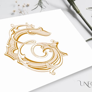 Puede incluir: Diseño dorado de la letra "G" adornada, con adornos y detalles decorativos. El diseño está impreso sobre una superficie blanca. La imagen incluye el texto "UNFOLD STUDIO" en la esquina inferior derecha.