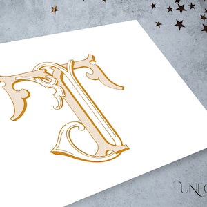 May include: A gold-colored, ornate, decorative letter T with a stylized, intricate design. The letter is on a white background.