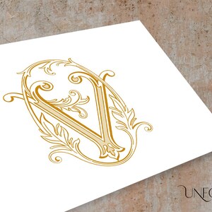 Op de afbeelding: Een sierlijke, decoratieve letter V in goud, met een bloemmotief.