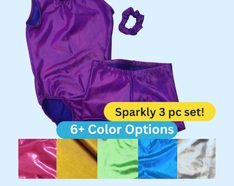 May include: A purple sleeveless leotard, matching shorts, and a scrunchie. The text reads Sparkly 3 pc set! 6+ Color Options. Below are fabric swatches in pink, gold, light green, blue, and silver. The set features a shiny, metallic finish.