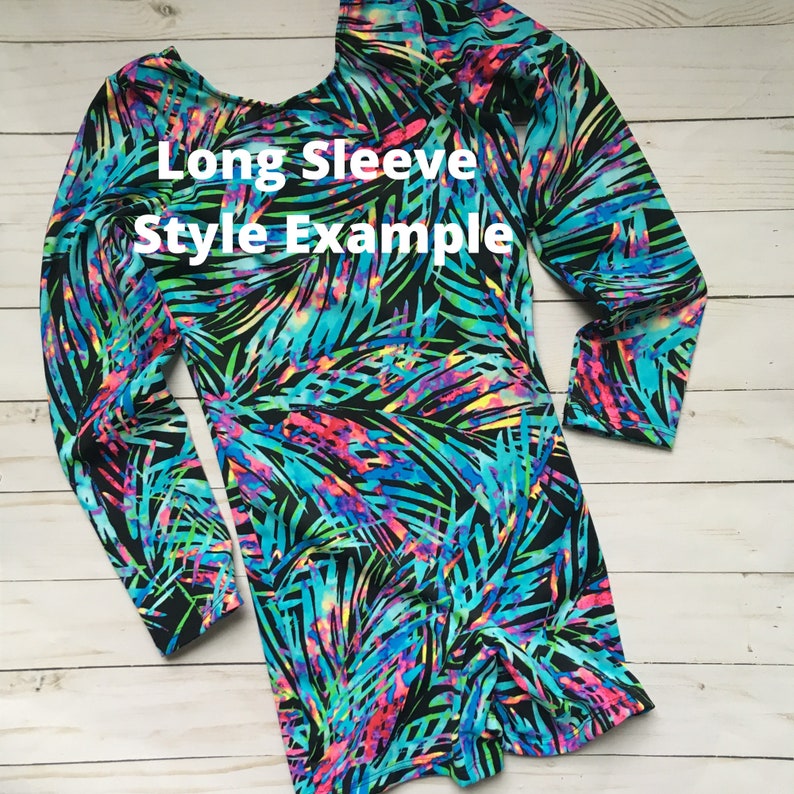 K&ouml;nnte beinhalten: Ein lang&auml;rmliger Einteiler mit schwarzem Hintergrund und einem bunten tropischen Blattmuster. Der Einteiler hat einen runden Ausschnitt und lange &Auml;rmel. Der Text "Long Sleeve Style Example" ist auf dem Einteiler sichtbar.